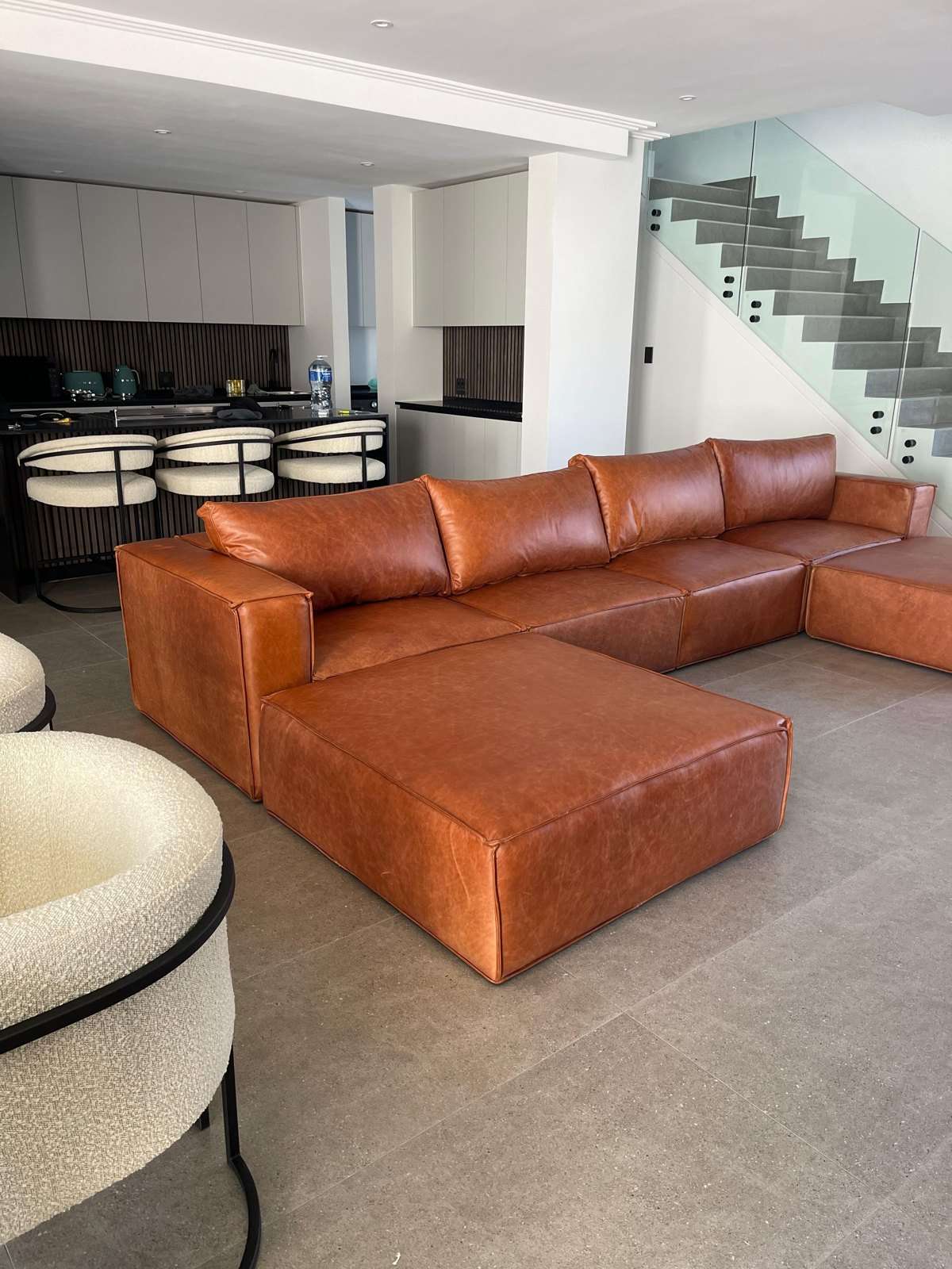 Tan leather corner couch back in a customer's lounge