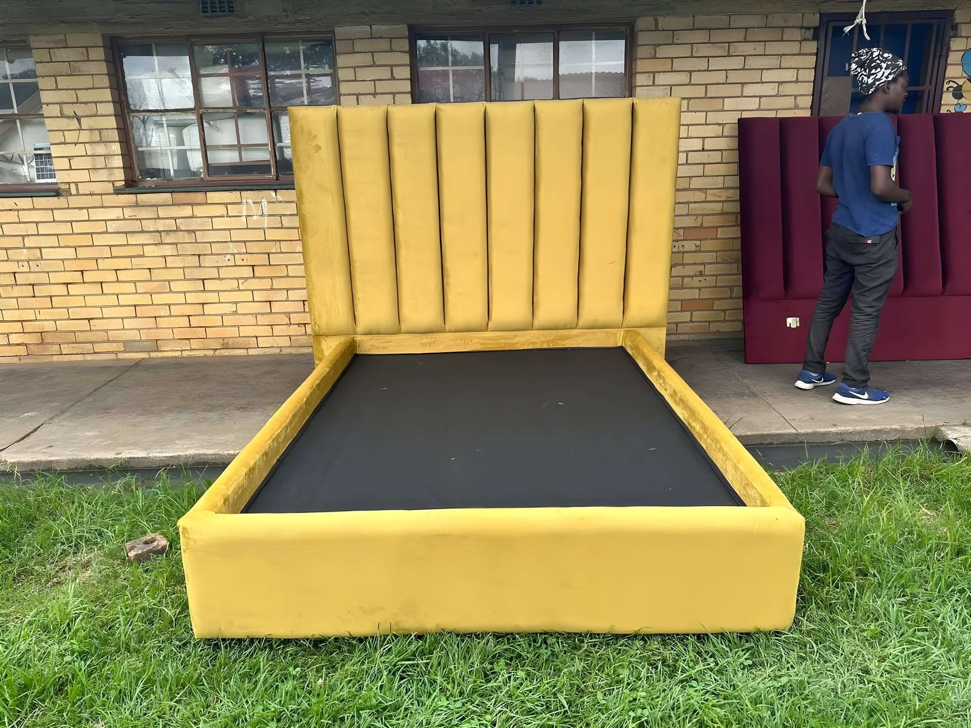 Yellow velvet bed base with a fluted headboard, and a pink fluted headboard behind it