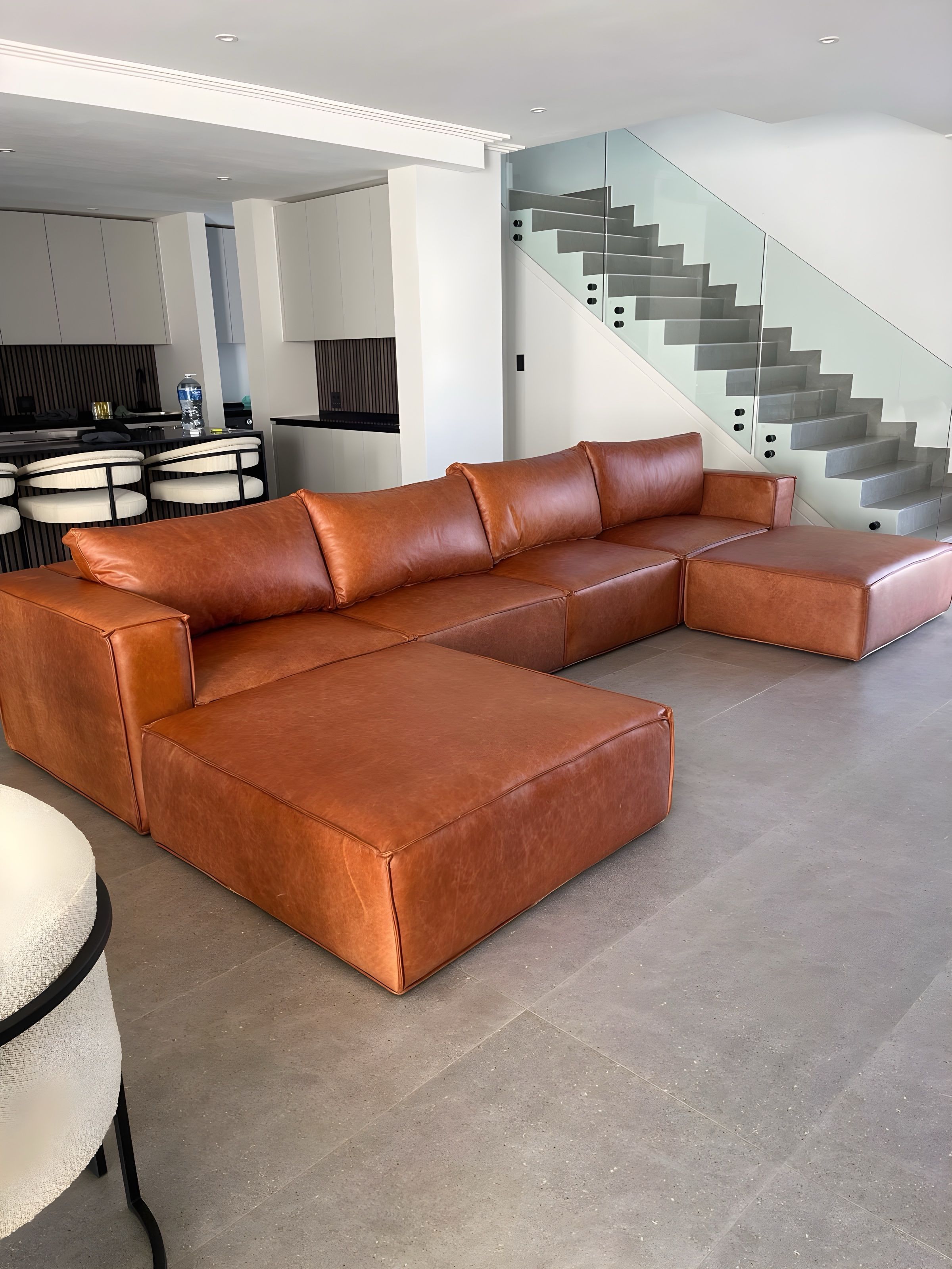 Tan leather corner couch in a bright lounge after we re-covered it