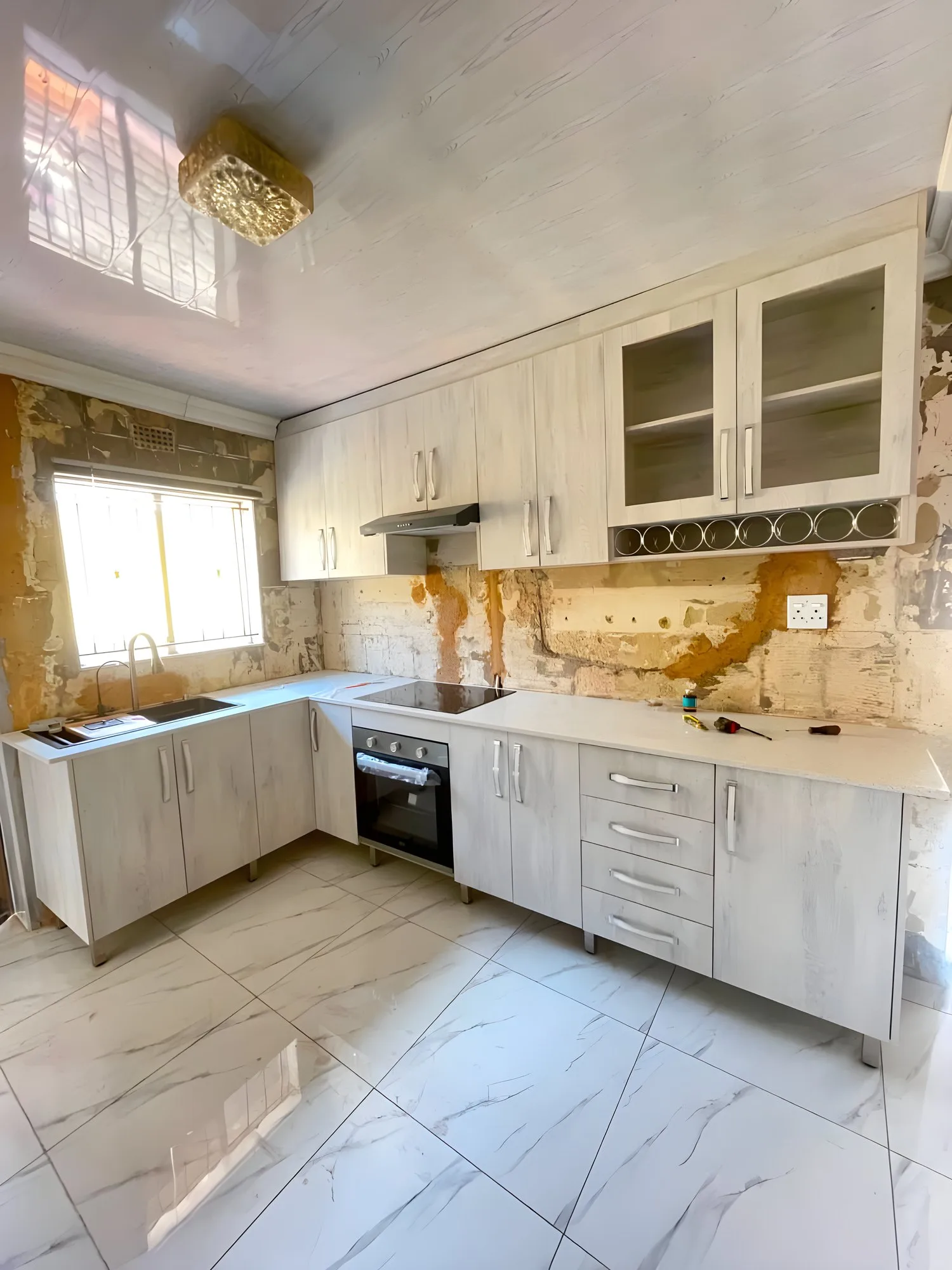 L-shaped whitewashed oak kitchen with glass-front wall cupboards