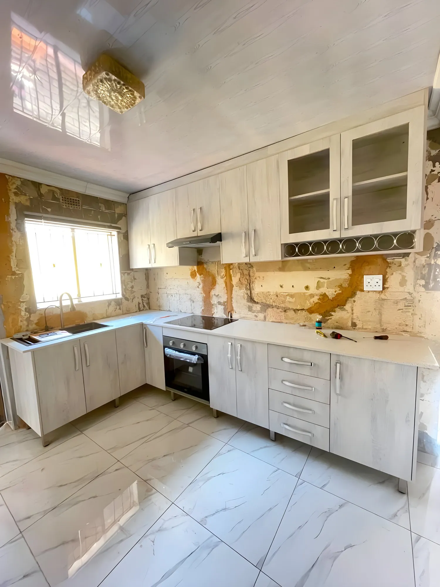 L-shaped whitewashed oak kitchen with glass-front wall cupboards