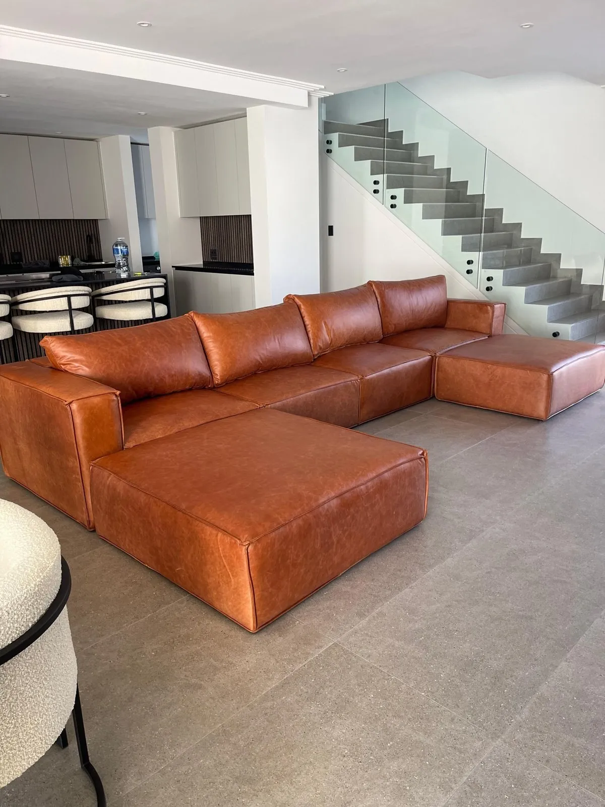 Tan leather corner couch back in a customer's lounge after reupholstery